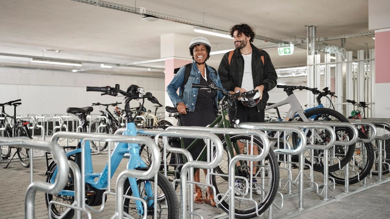 Zwei JobRadler:innen steigen aufs Fahrrad im Fahrradkeller. Zwei JobRadler:innen steigen aufs Fahrrad im Fahrradkeller.