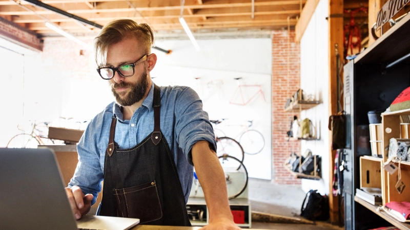 Fachhändler im Fahrradgeschäft steht am Tresen und schaut komnzentriert in den Laptop. Er nutzt die Partner API